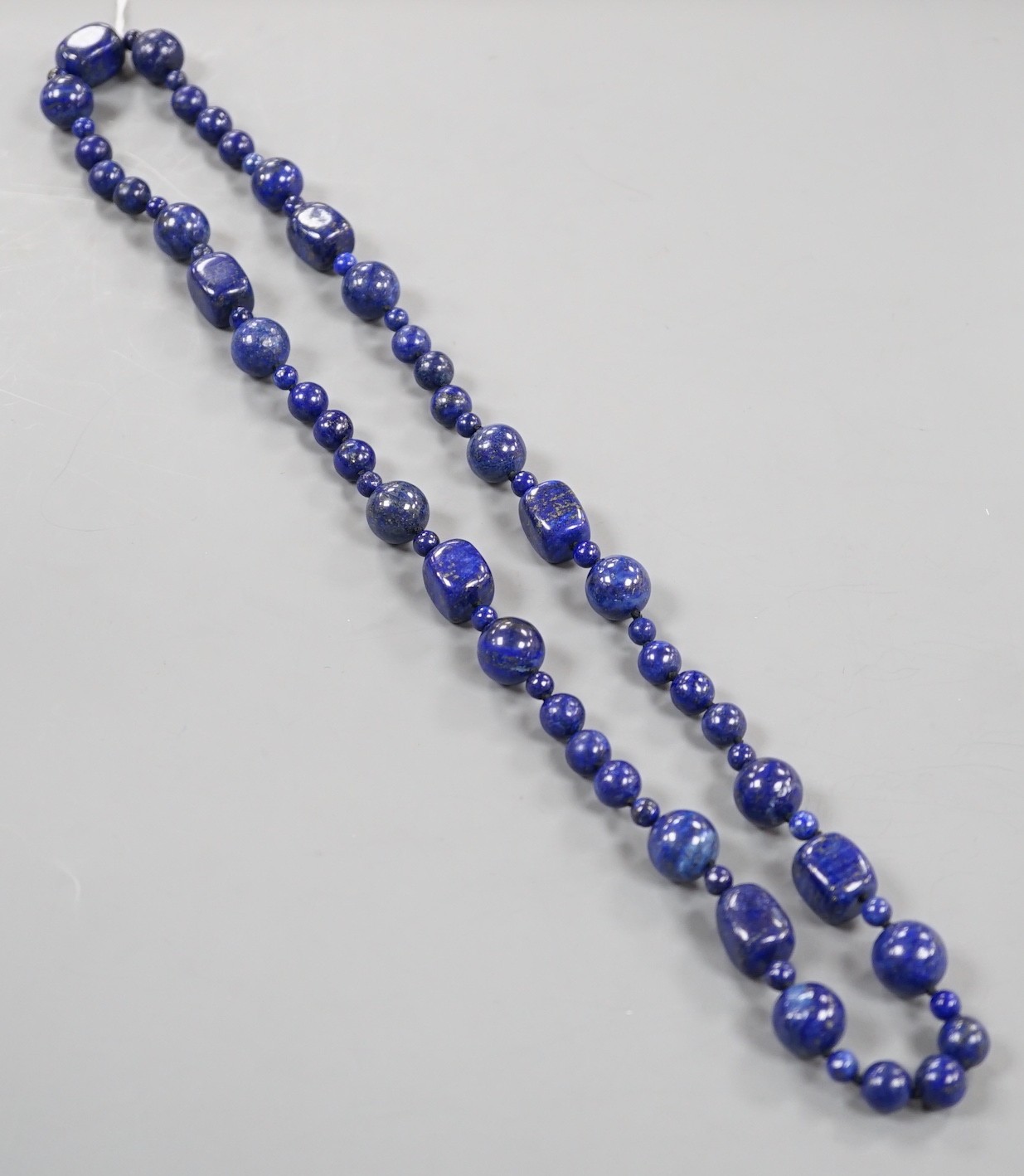 A single strand lapis lazuli round and barrel bead necklace, 72cm.